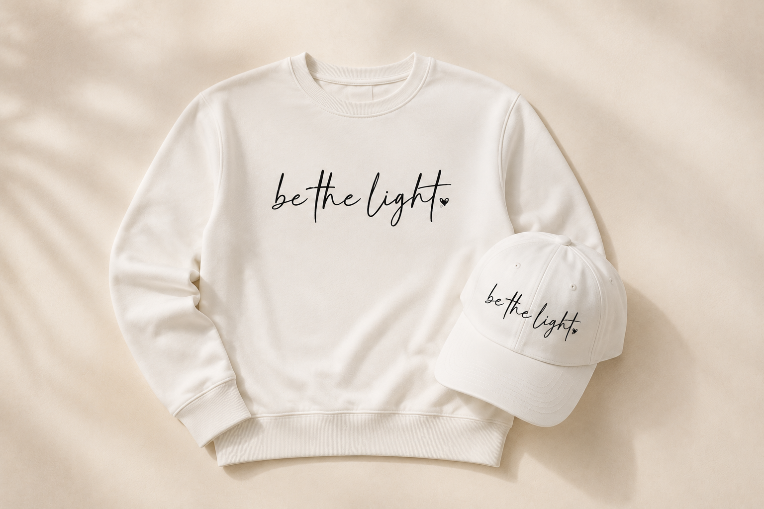 White sweatshirt and cap with 'be the light' text.