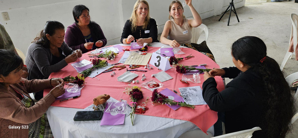 Group of people sitting around a table with flowers and name tags in an indoor setting.